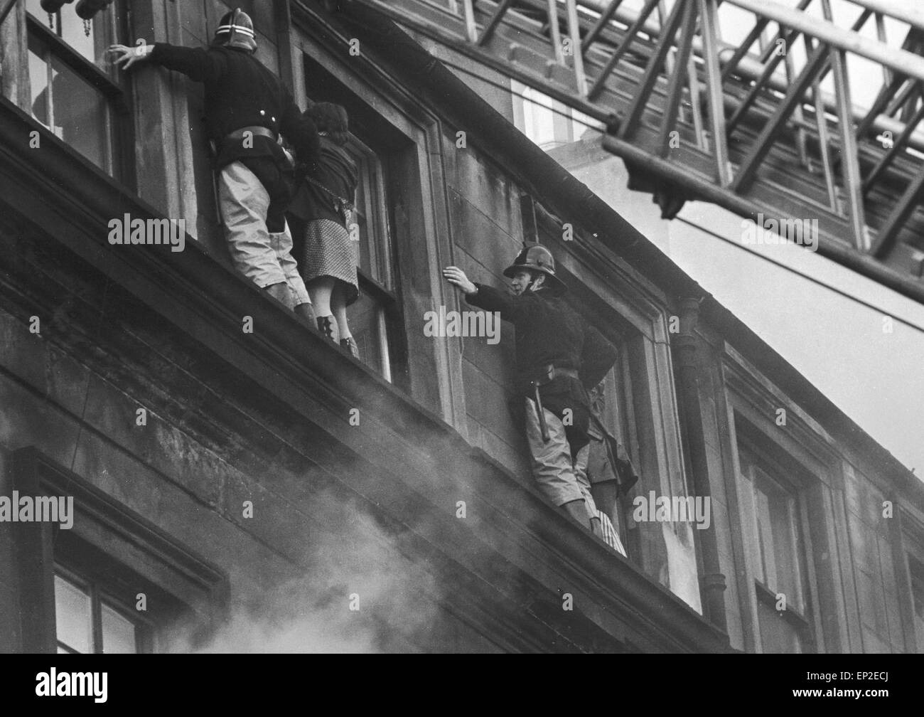 Incendie à Maryhill Road Glasgow. Feu dans un magasin de meubles inoccupés se propager le long de la rangée de boutiques et de piégeage des familles dans leurs maisons ci-dessus. Cinquante familles sont sans abri et d'une femme et d'un officier pompier ont perdu la vie. Samedi, 18 novembre 1972. Pompiers, tenter de sauver une femme d'un rebord de fenêtre au cours de l'incendie. Banque D'Images