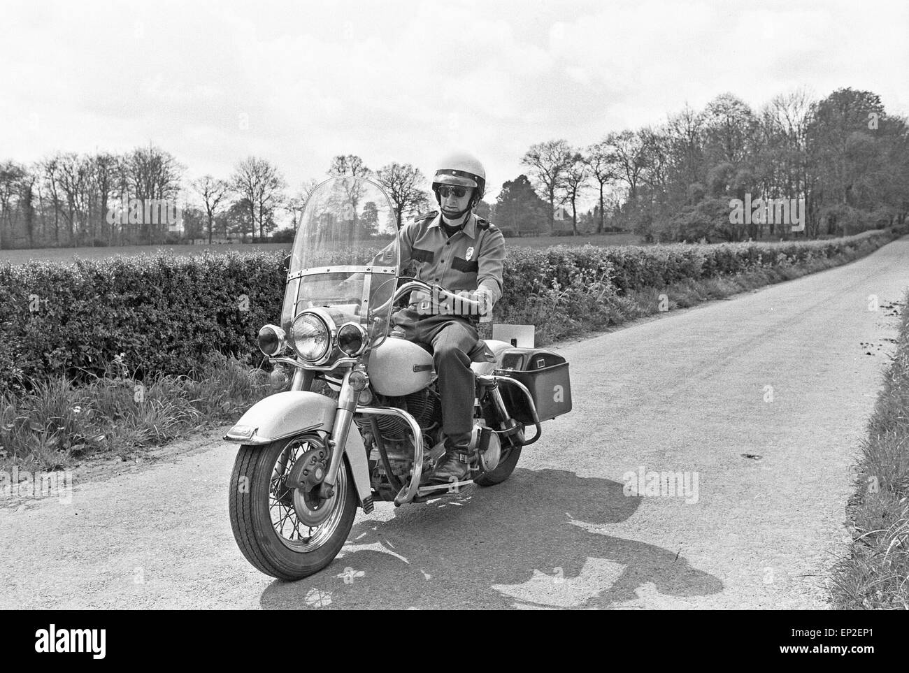 La police américaine enthusiast John Hayes portant l'uniforme de la ville  agent de police et le casque blanc comme il va faire un tour sur sa moto  Harley Davidson. Mai 1977 Photo