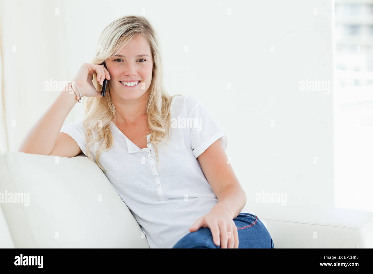 Une femme qui parle sur son téléphone en souriant et regardant la caméra Banque D'Images Une femme qui parle sur son téléphone en souriant et regardant la caméra Banque D'Images