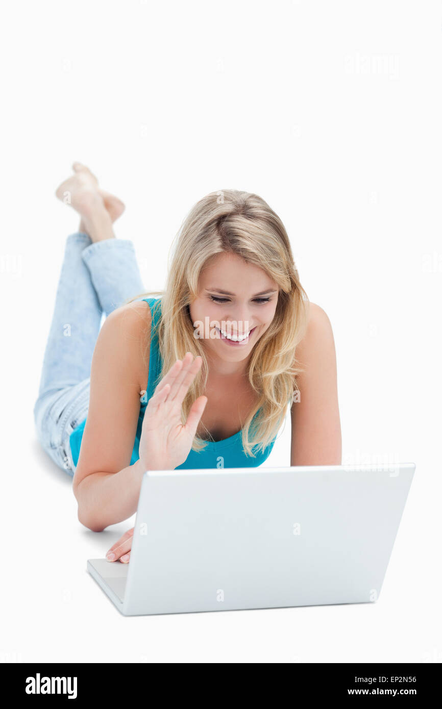 Une femme avec un ordinateur portable a la main et est couchée sur le plancher Banque D'Images Une femme avec un ordinateur portable a la main et est couchée sur le plancher Banque D'Images