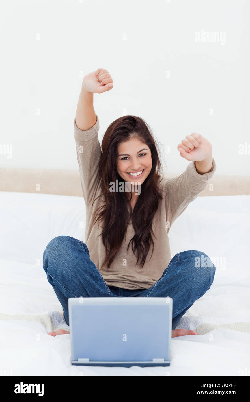 Femme regarde droit devant alors qu'elle célèbre en face de son ordinateur portable Banque D'Images Femme regarde droit devant alors qu'elle célèbre en face de son ordinateur portable Banque D'Images