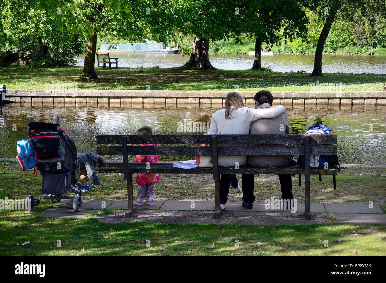 Une jeune famille s'asseoir sur un banc près de la rivière Thames à Windsor, Berkshire Banque D'Images