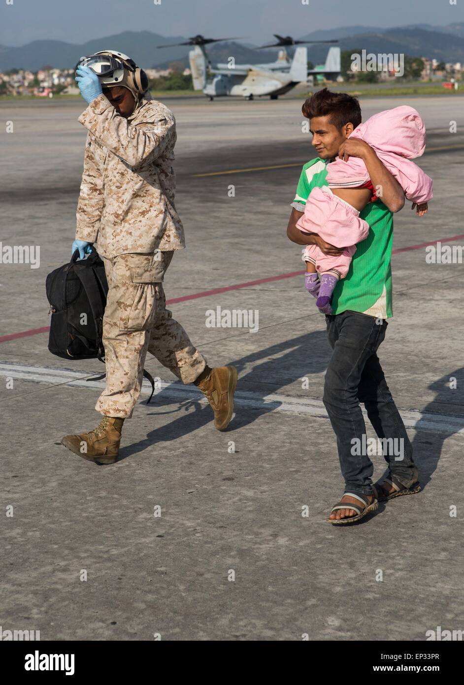 Katmandou, Népal. 13 mai, 2015. Un U.S. Marine à la Force opérationnelle 505 aide un homme et son enfant à un triage médical à l'aéroport international de Tribhuvan, 12 mai 2015 à Katmandou, au Népal. 7.3 Une ampleur aftershock séisme a frappé le royaume après la séisme de magnitude 7,8 le 25 avril. Banque D'Images