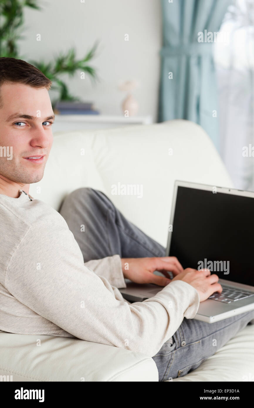 Portrait d'un homme allongé sur le canapé avec un ordinateur portable Banque D'Images