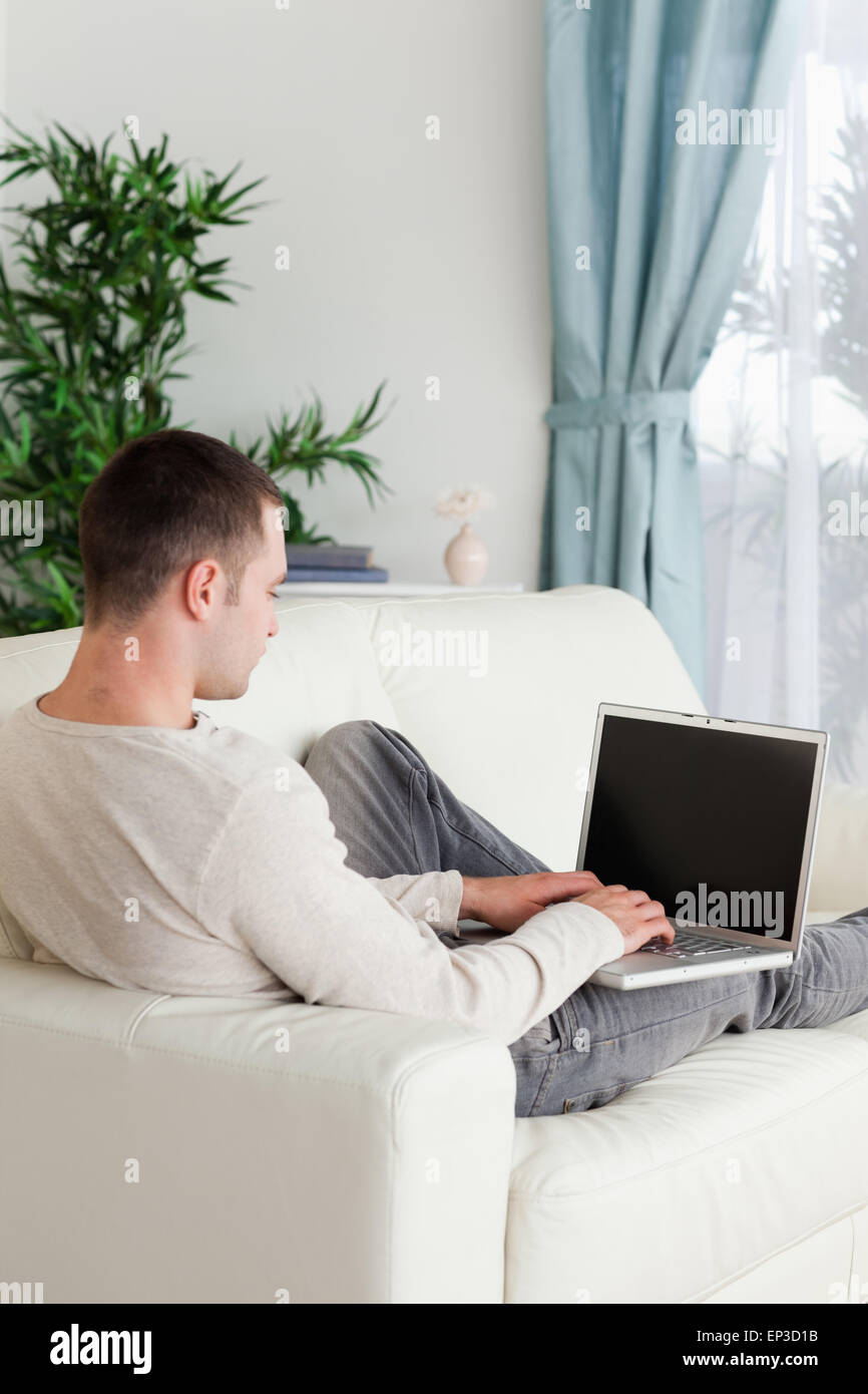 Portrait d'un homme allongé sur son canapé à l'aide d'ordinateur Banque D'Images