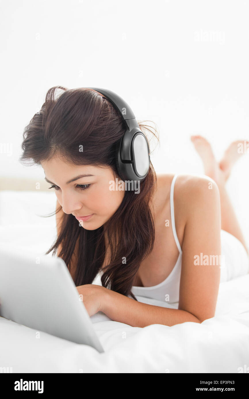 Femme à l'aide d'une tablette et d'écouteurs avec les jambes croisées Banque D'Images Femme à l'aide d'une tablette et d'écouteurs avec les jambes croisées Banque D'Images