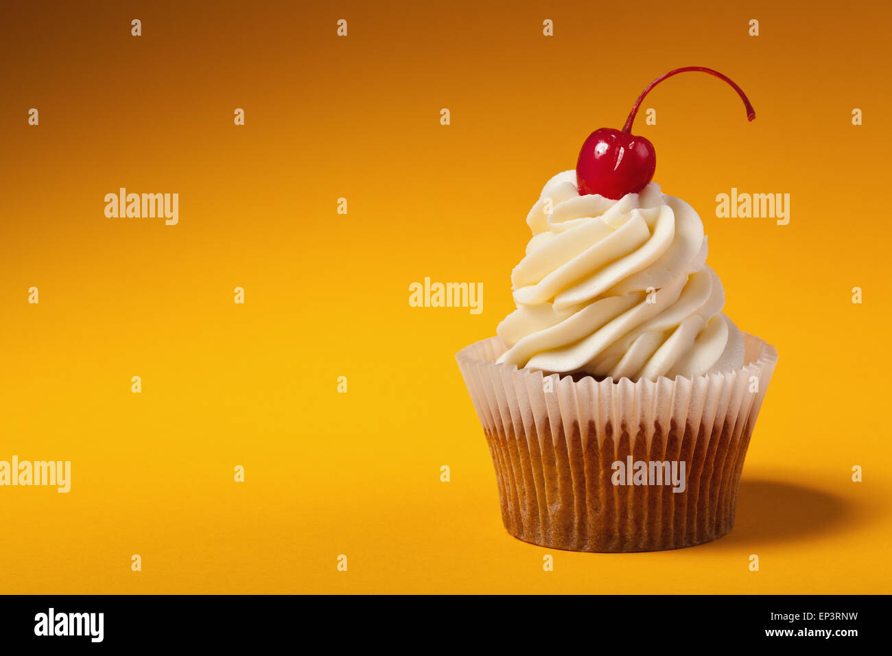 Avec cupcake cerise rouge isolé sur orange Banque D'Images
