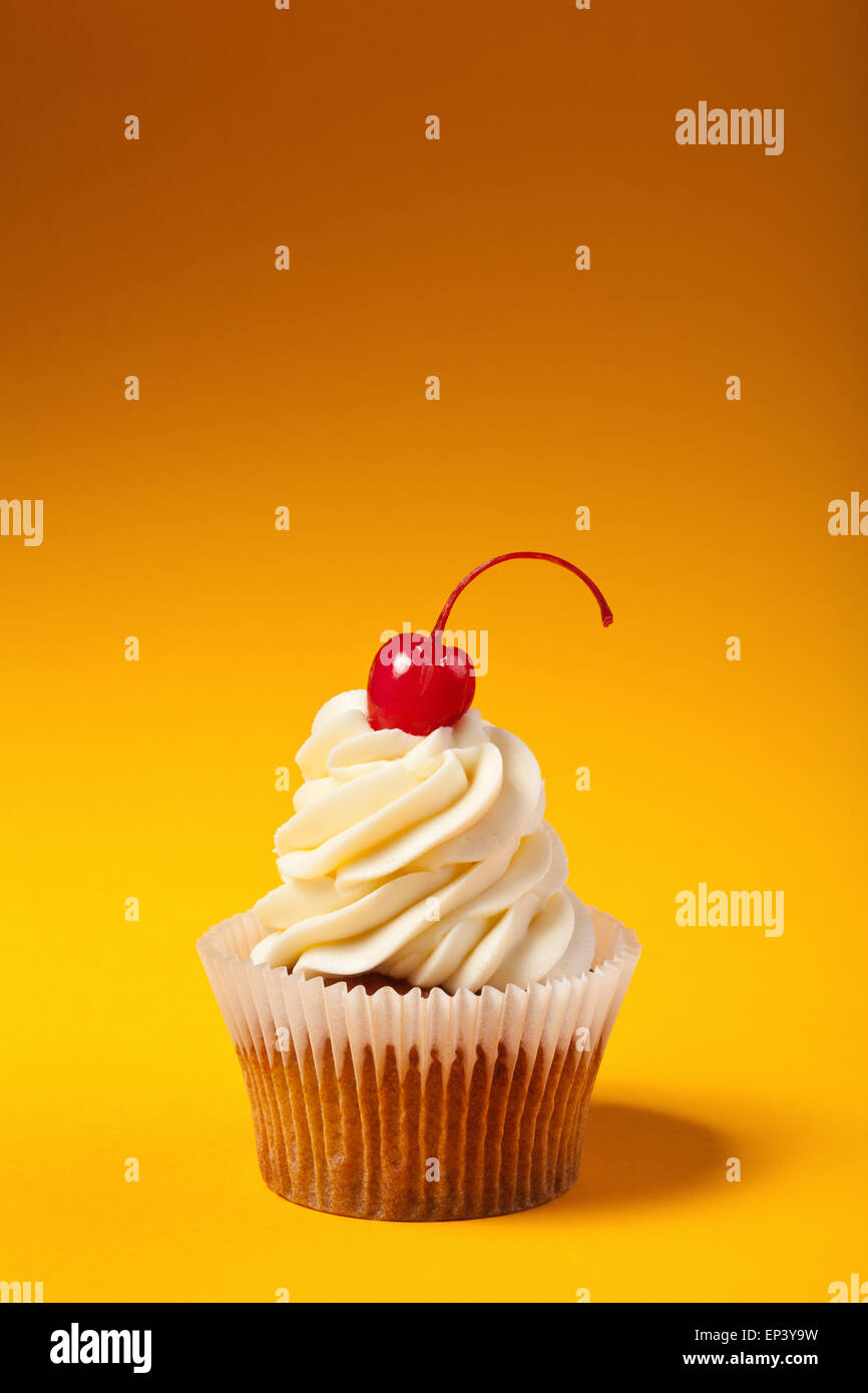 Avec cupcake cerise rouge isolé sur orange Banque D'Images