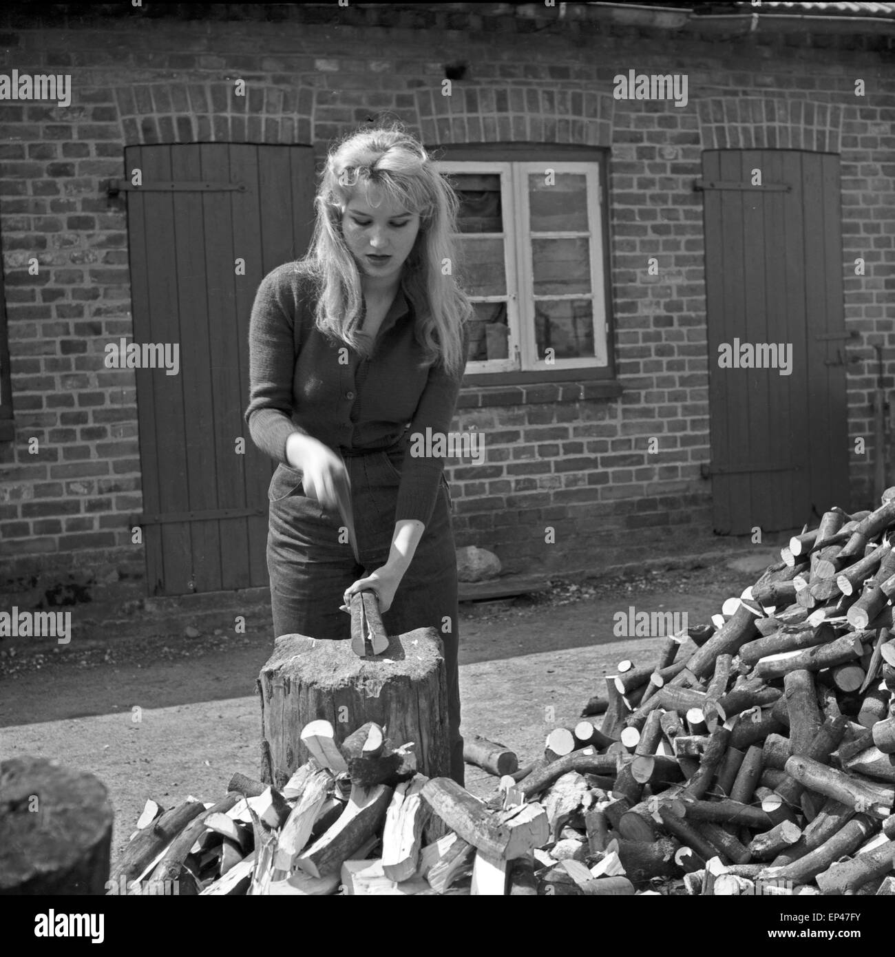 Deutsche Schauspielerin Karin Stoltenfeldt Holzhacken Haus, Deutschland 1950er Jahre. L'actrice allemande Karin puce Stoltenfeldt Banque D'Images