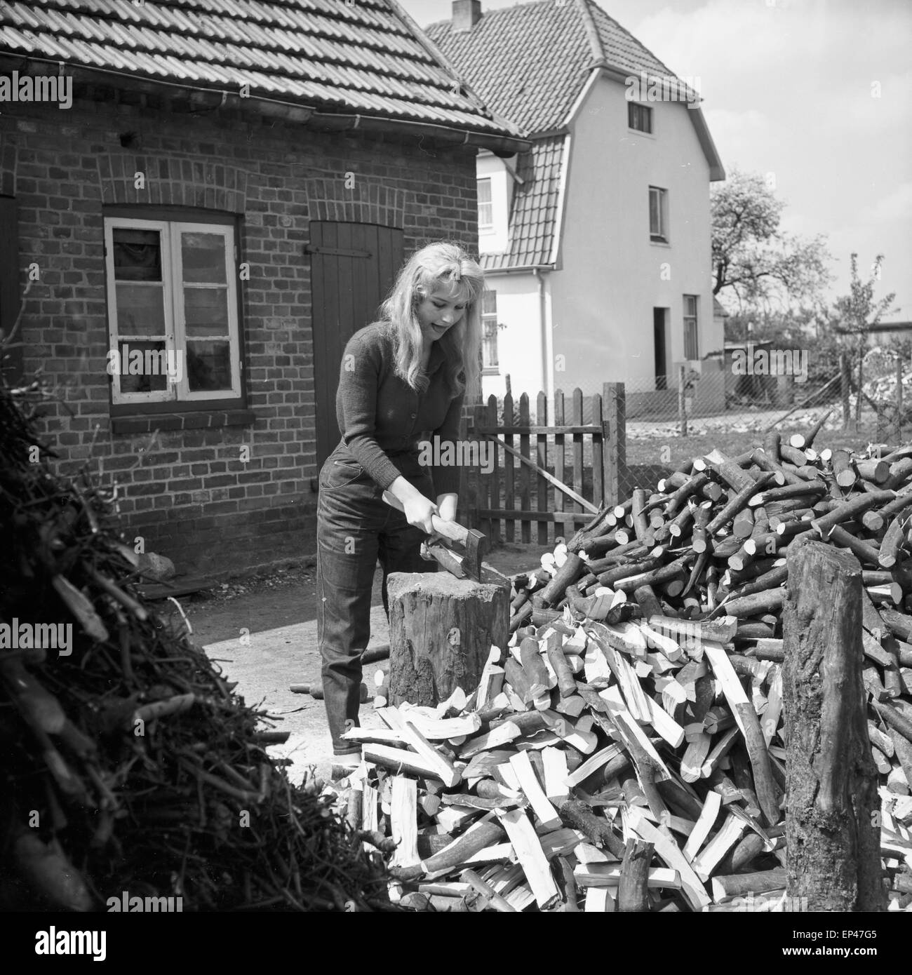 Deutsche Schauspielerin Karin Stoltenfeldt Holzhacken Haus, Deutschland 1950er Jahre. L'actrice allemande Karin puce Stoltenfeldt Banque D'Images