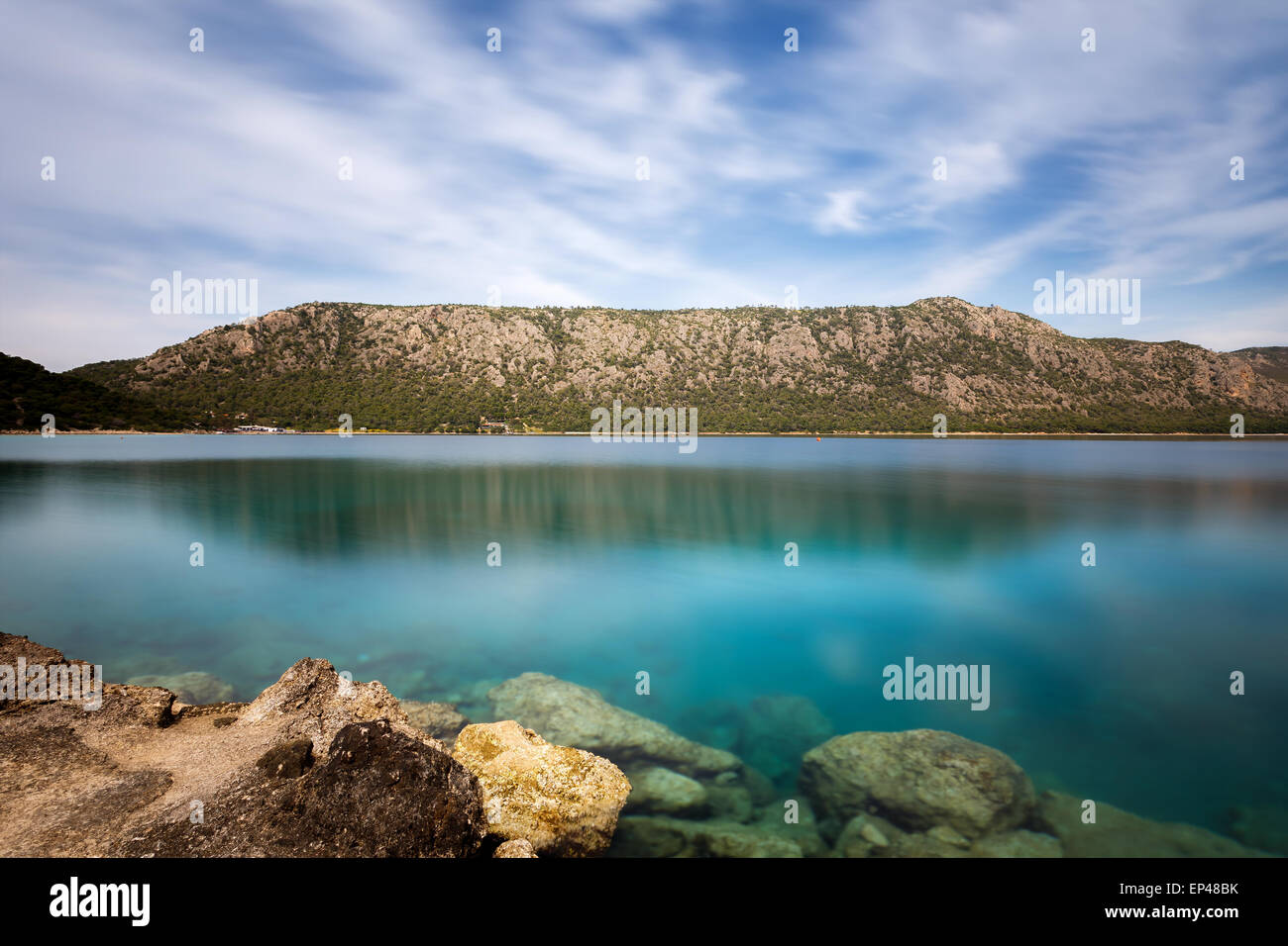 Belles eaux claires de lac Vouliagmeni près de Loutraki, Grèce contre un ciel nuageux Banque D'Images