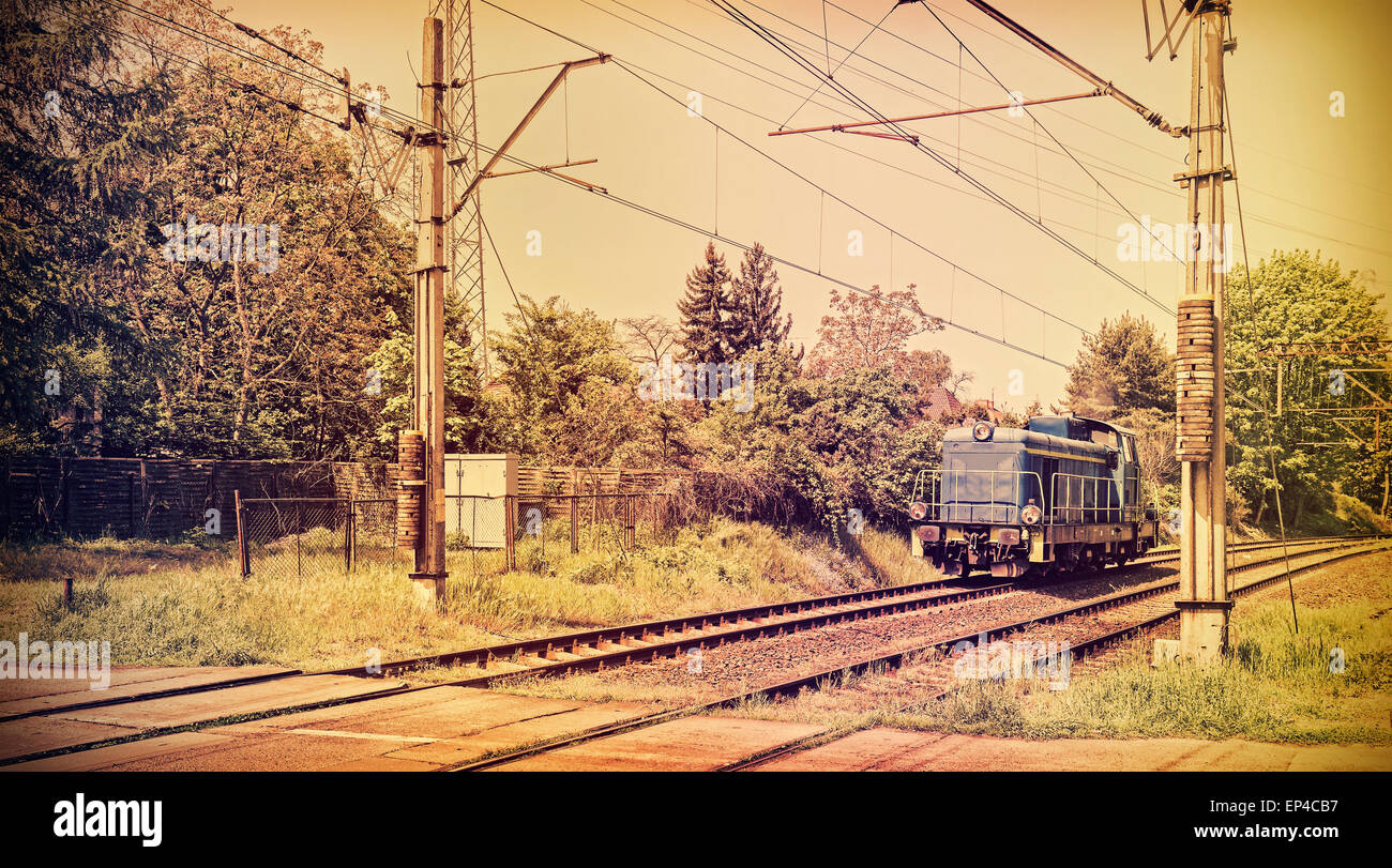 Retro photo aux couleurs d'une locomotive sur le passage à niveau, style vieux film. Banque D'Images