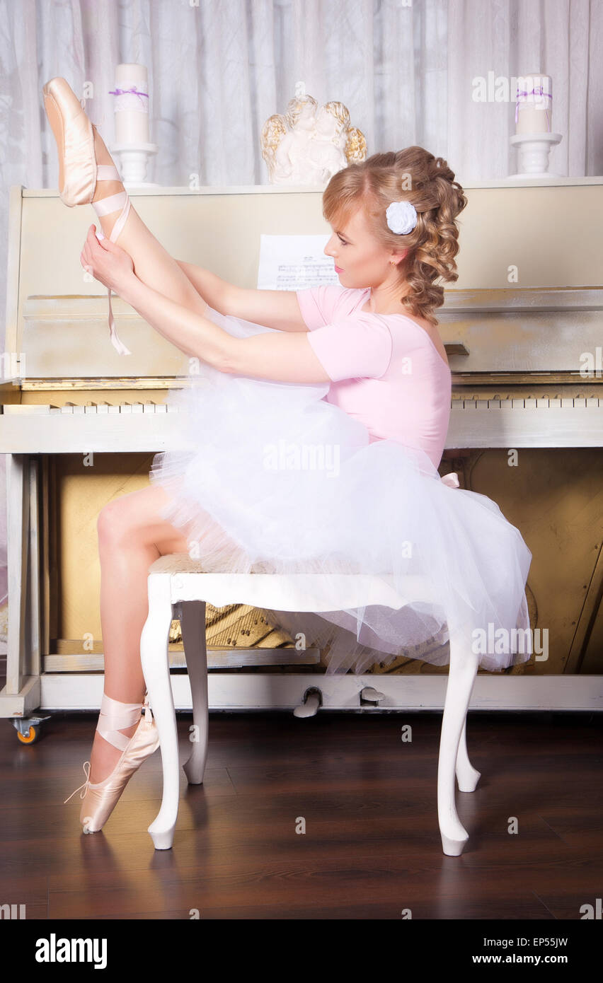 Ballerine à pointe shoes assis sur une chaise près du piano Banque D'Images