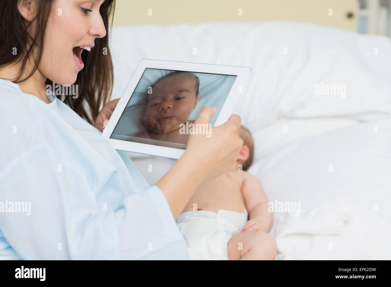 Smiling mother à l'aide d'un comprimé pour prendre une photo d'un bébé nouveau-né Banque D'Images Smiling mother à l'aide d'un comprimé pour prendre une photo d'un bébé nouveau-né Banque D'Images