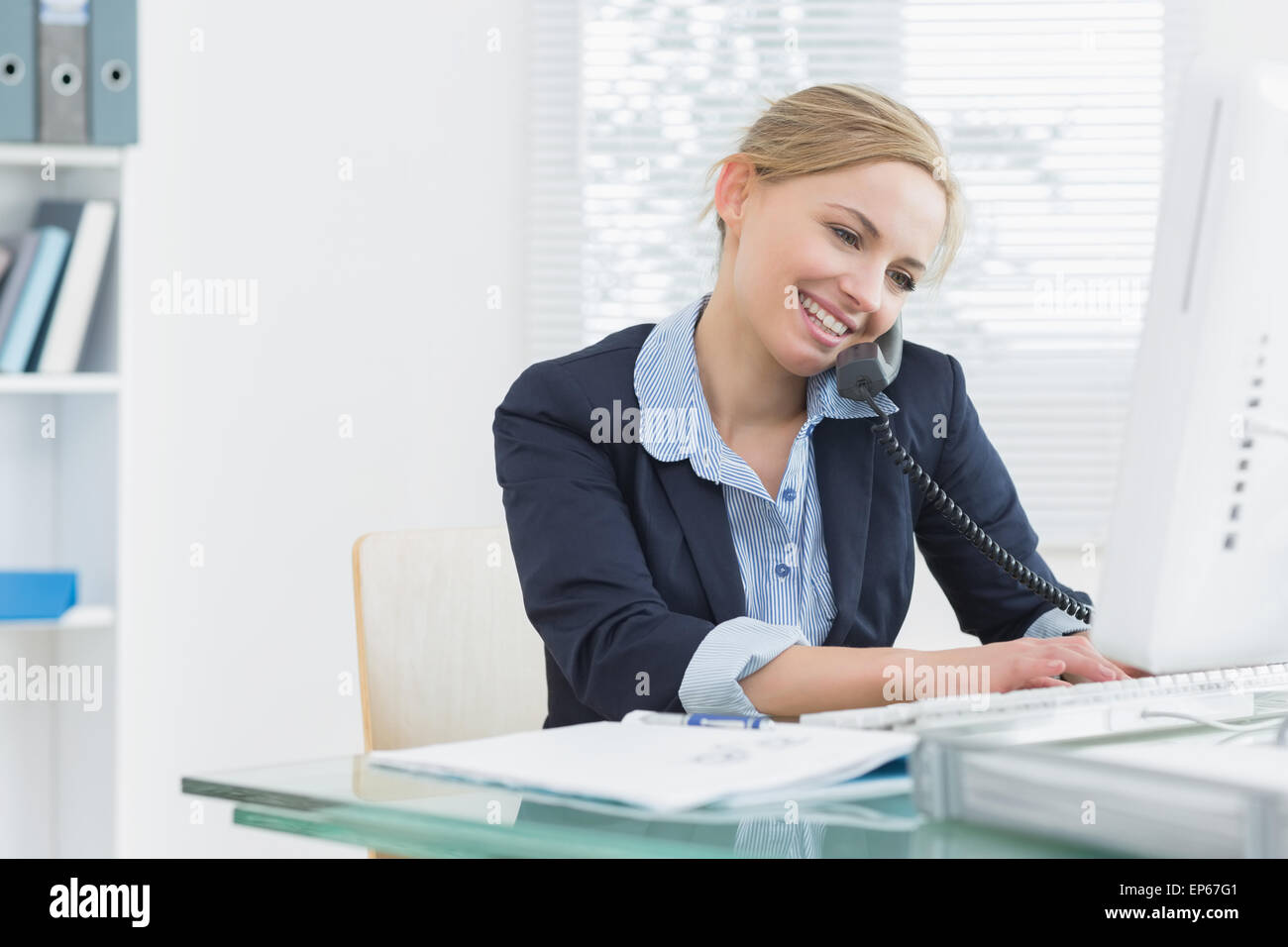 Téléphone fixe à l'aide de la femme et de l'ordinateur au bureau Banque D'Images