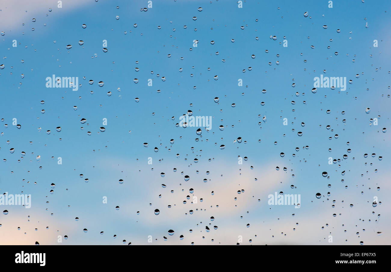 Gouttes de pluie sur un carreau de fenêtre en face d'un ciel bleu Banque D'Images