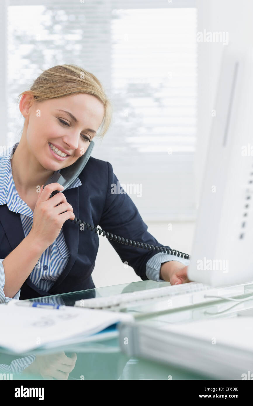 Téléphone fixe à l'aide de la femme et de l'ordinateur au bureau Banque D'Images