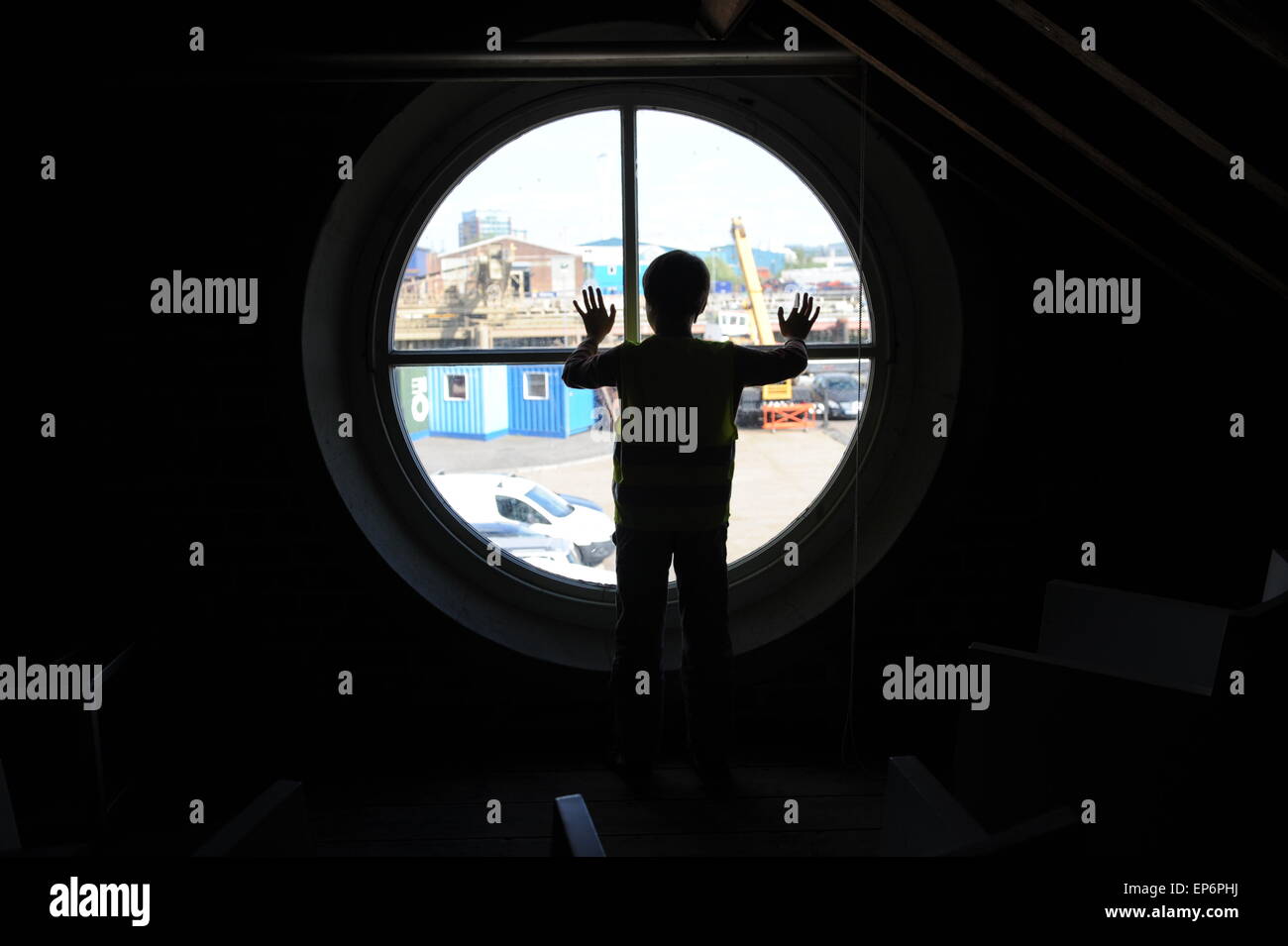 10 ans garçon anglais regardant par la fenêtre du phare dans Trinity Buoy Wharf phare. Banque D'Images