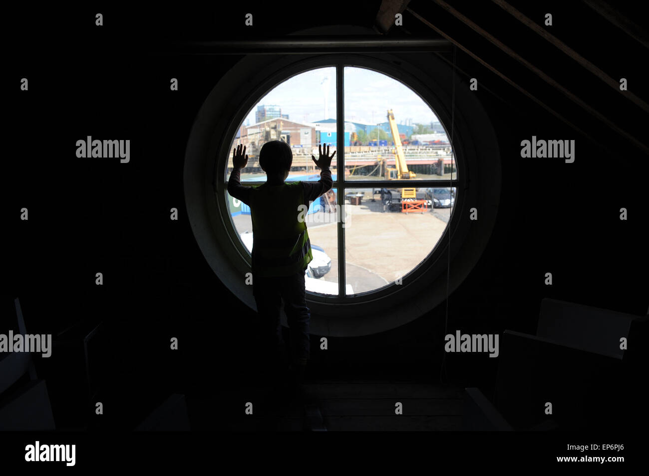 10 ans garçon anglais regardant par la fenêtre du phare dans Trinity Buoy Wharf phare. Banque D'Images