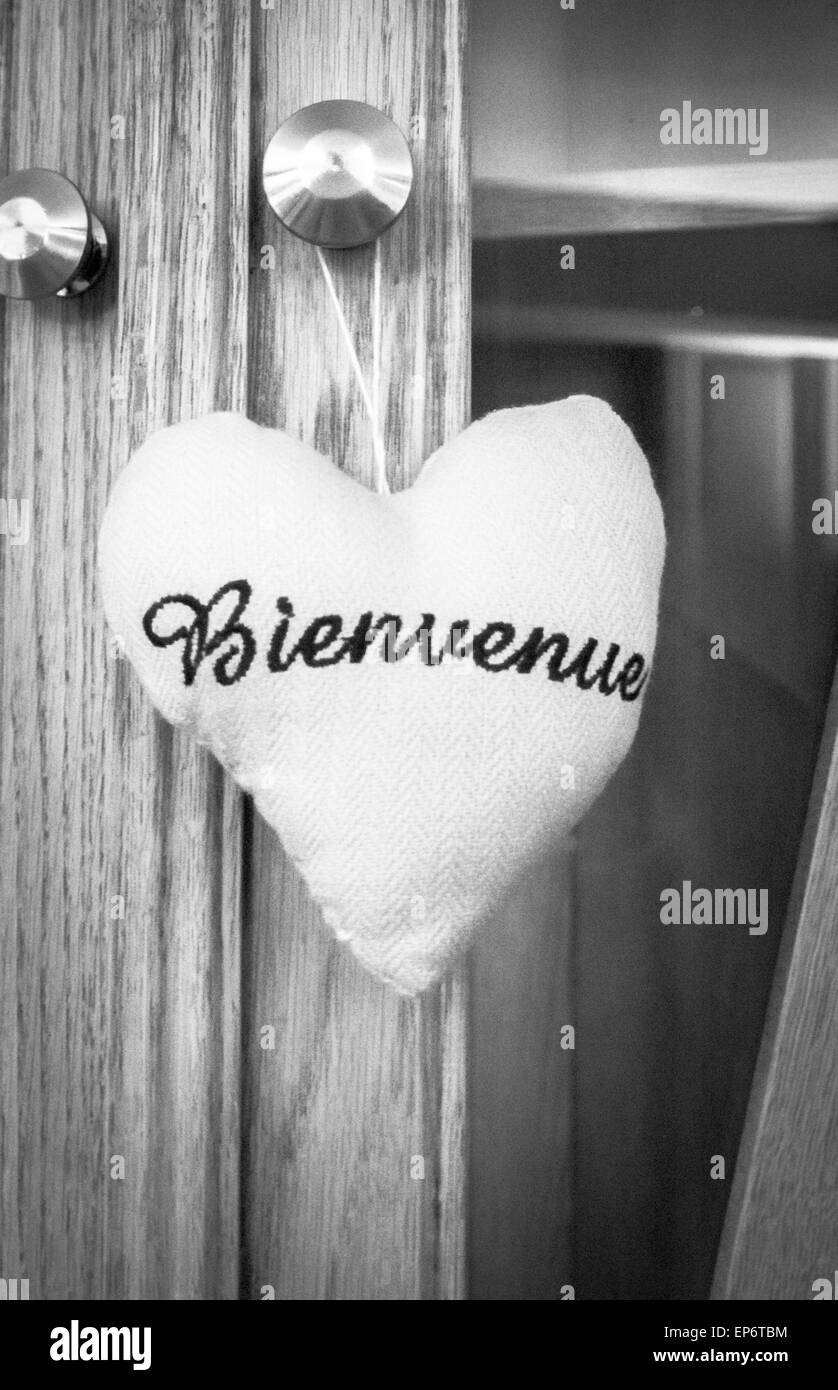 Un matériau en peluche coeur avec le mot bienvenue (français) Bienvenue à brodé sur elle, en noir et blanc Banque D'Images
