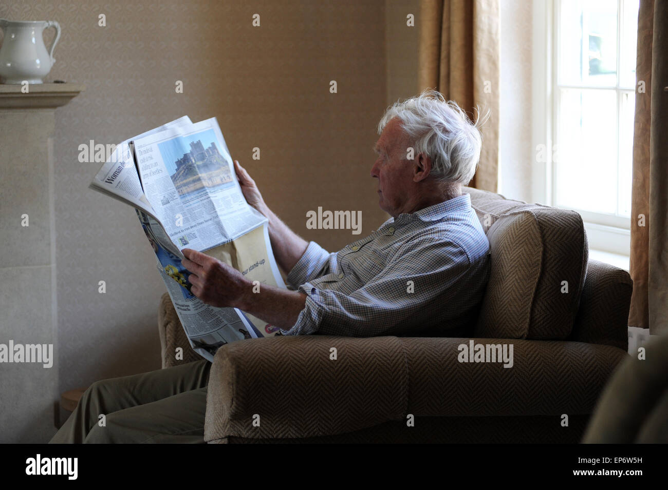 Personne âgée retraitée lire le Daily Telegraph à la maison dans le Nord du Yorkshire. Banque D'Images