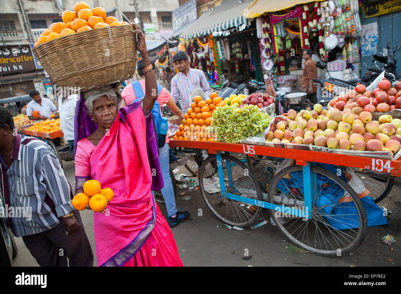 Femme dans un sari rose vente d'oranges au Devaraja marché de fruits et légumes à Mysore Banque D'Images