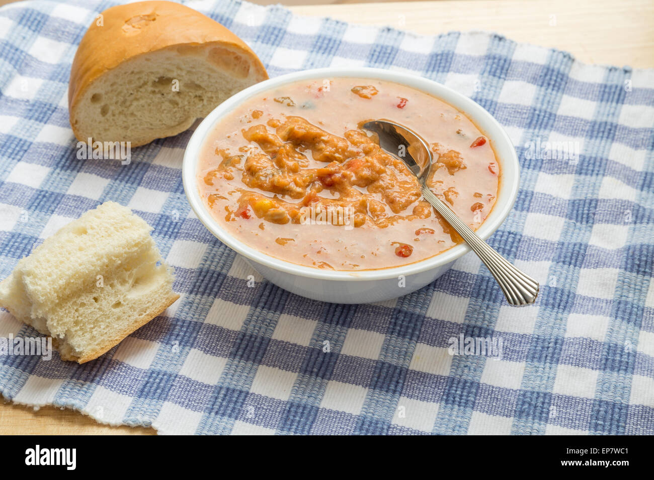 Un bol de soupe tortilla poulet sur un chiffon bleu vérifié dans la fenêtre de la lumière avec du pain français Banque D'Images