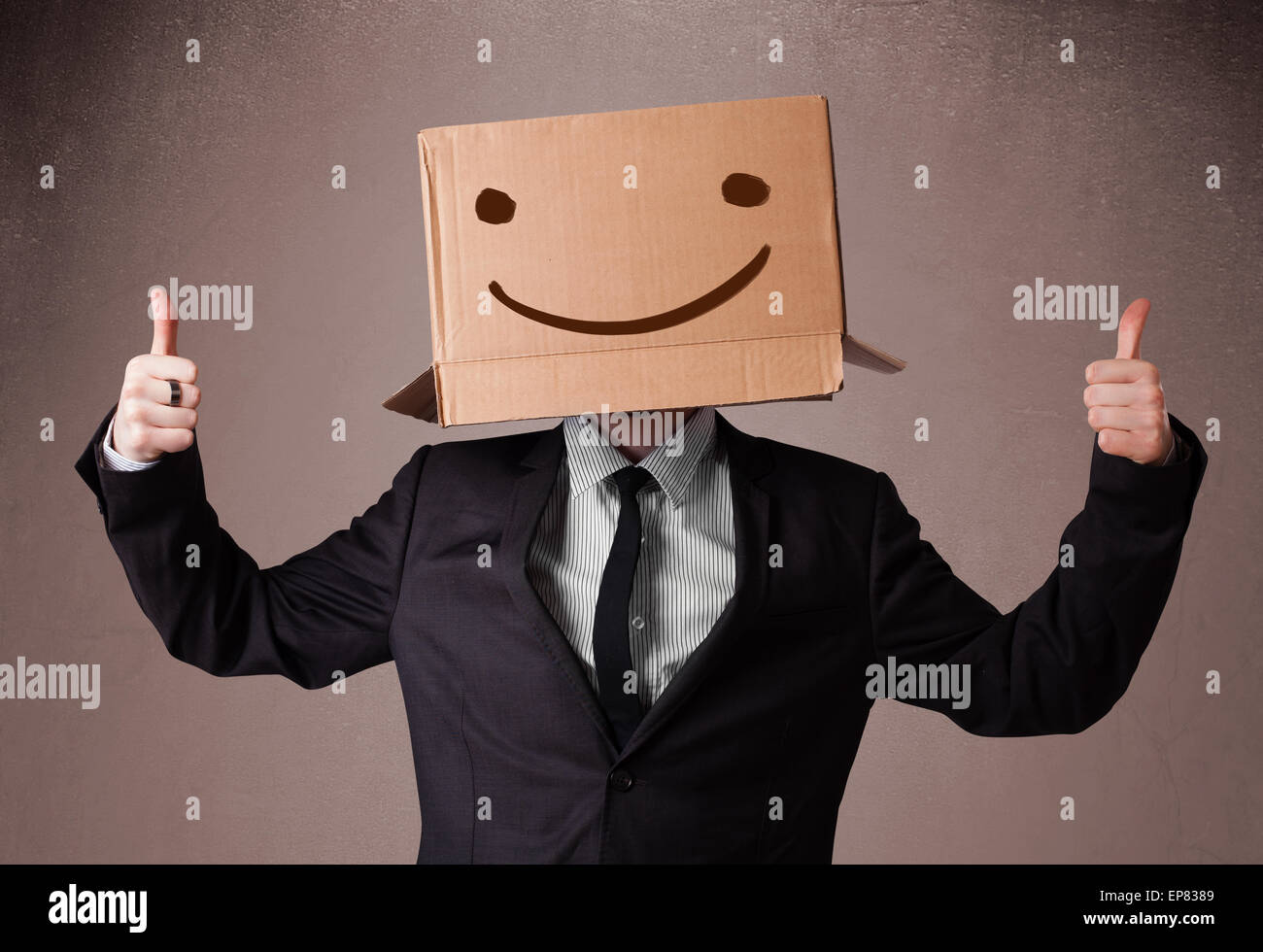 Businessman gesturing avec une boîte en carton sur la tête avec des smiley face Banque D'Images