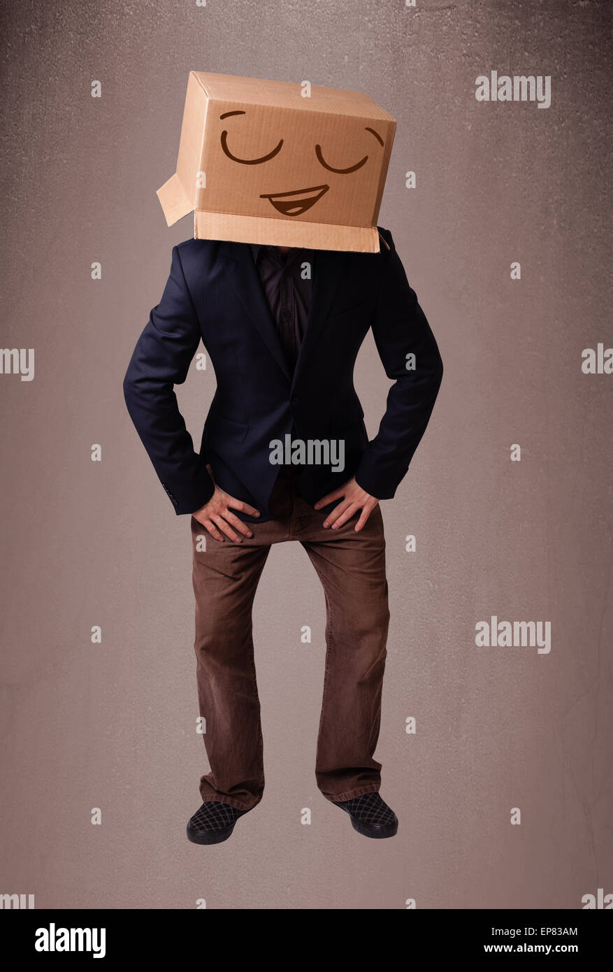Jeune homme gesticulant avec une boîte en carton sur la tête avec des smiley face Banque D'Images