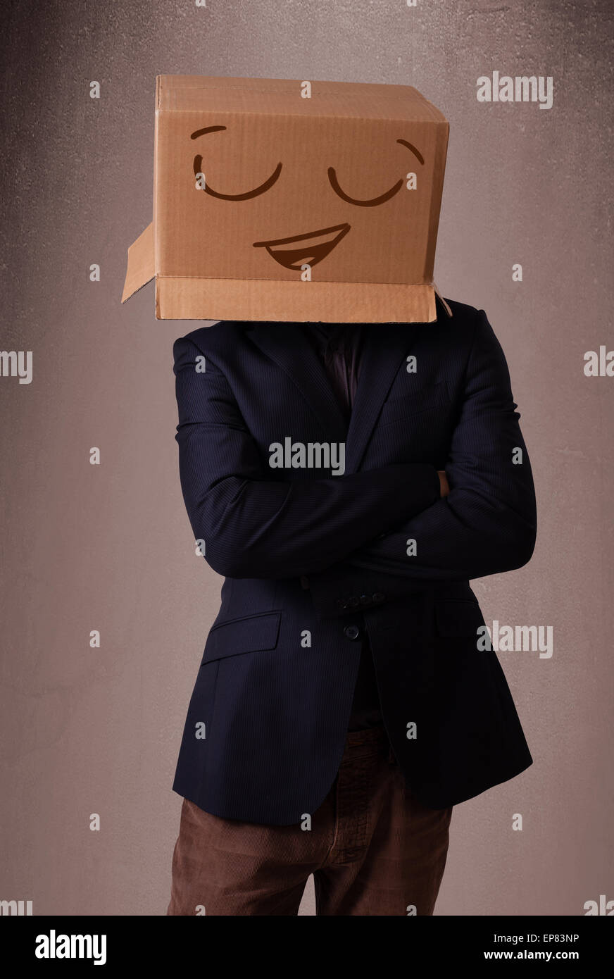 Jeune homme gesticulant avec une boîte en carton sur la tête avec des smiley face Banque D'Images