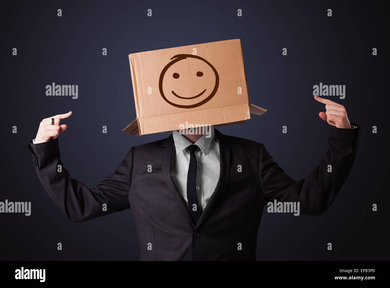 Businessman gesturing avec une boîte en carton sur la tête avec des smiley face Banque D'Images