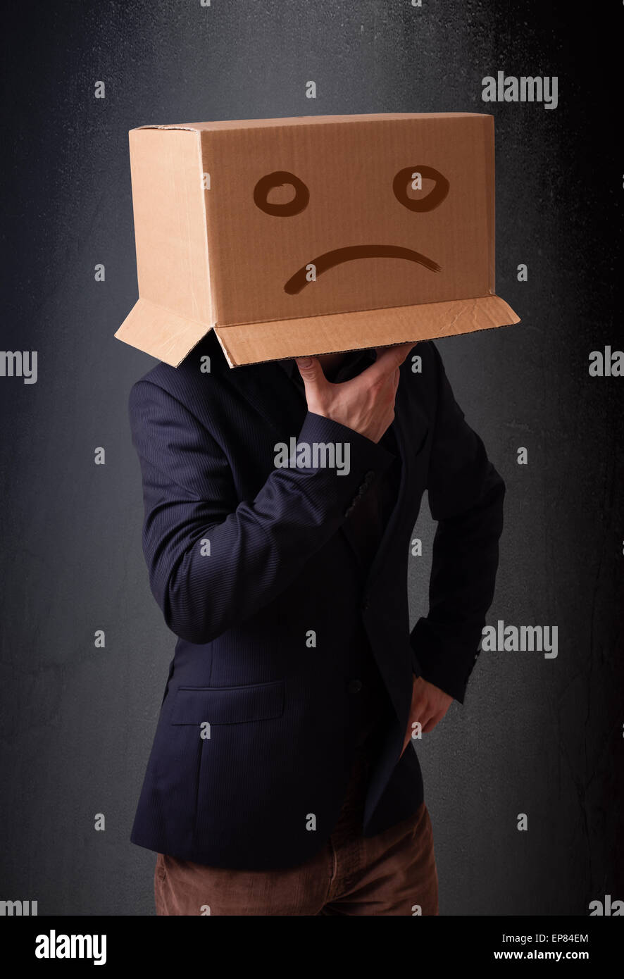Jeune homme brun avec une boîte en carton sur la tête avec visage triste Banque D'Images