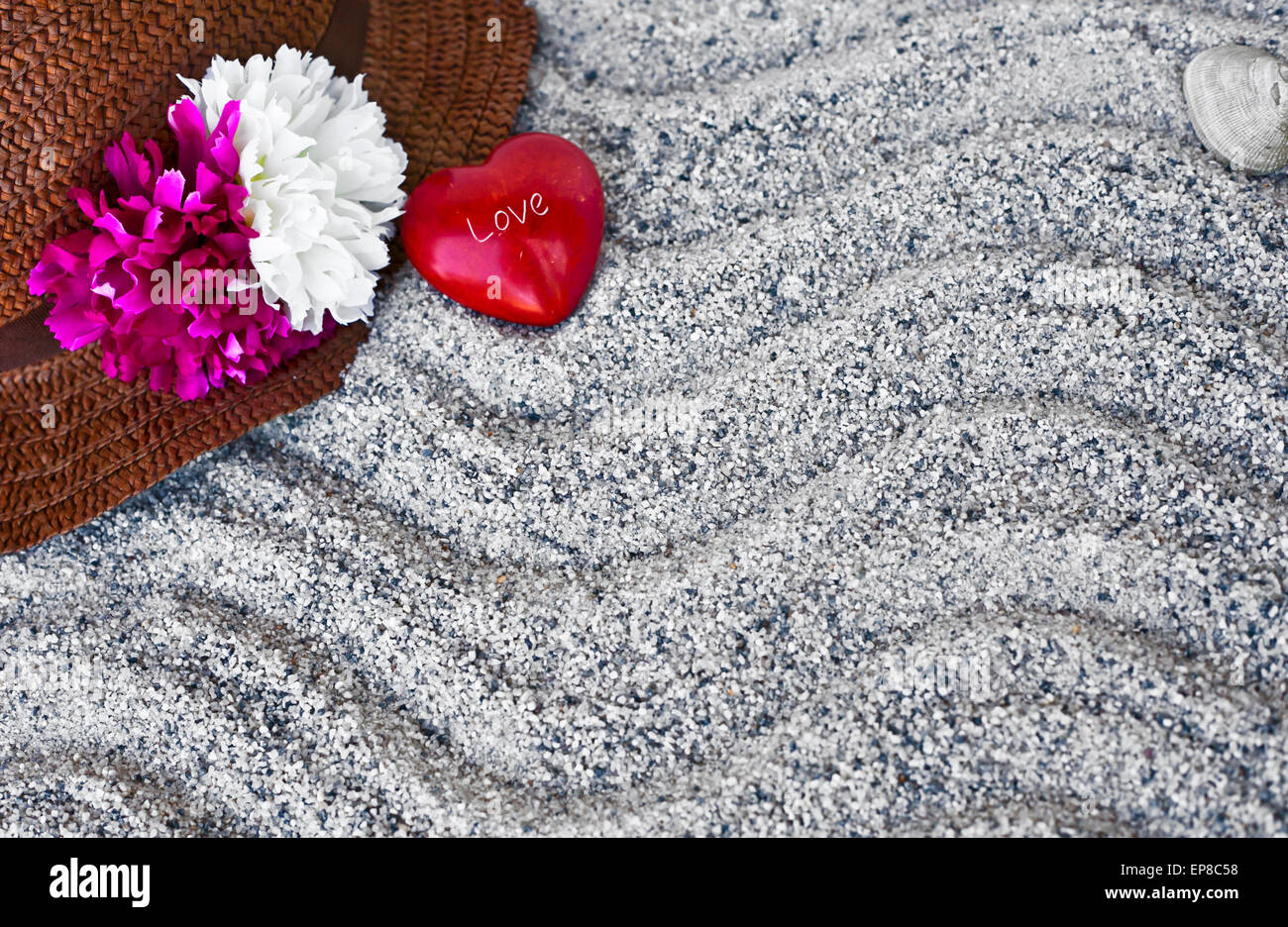 Fond de plage avec du sable de plage, copyspace thème d'été, chapeau de paille et peu de coeur rouge avec des lettres l'amour sur la texture du sable Banque D'Images