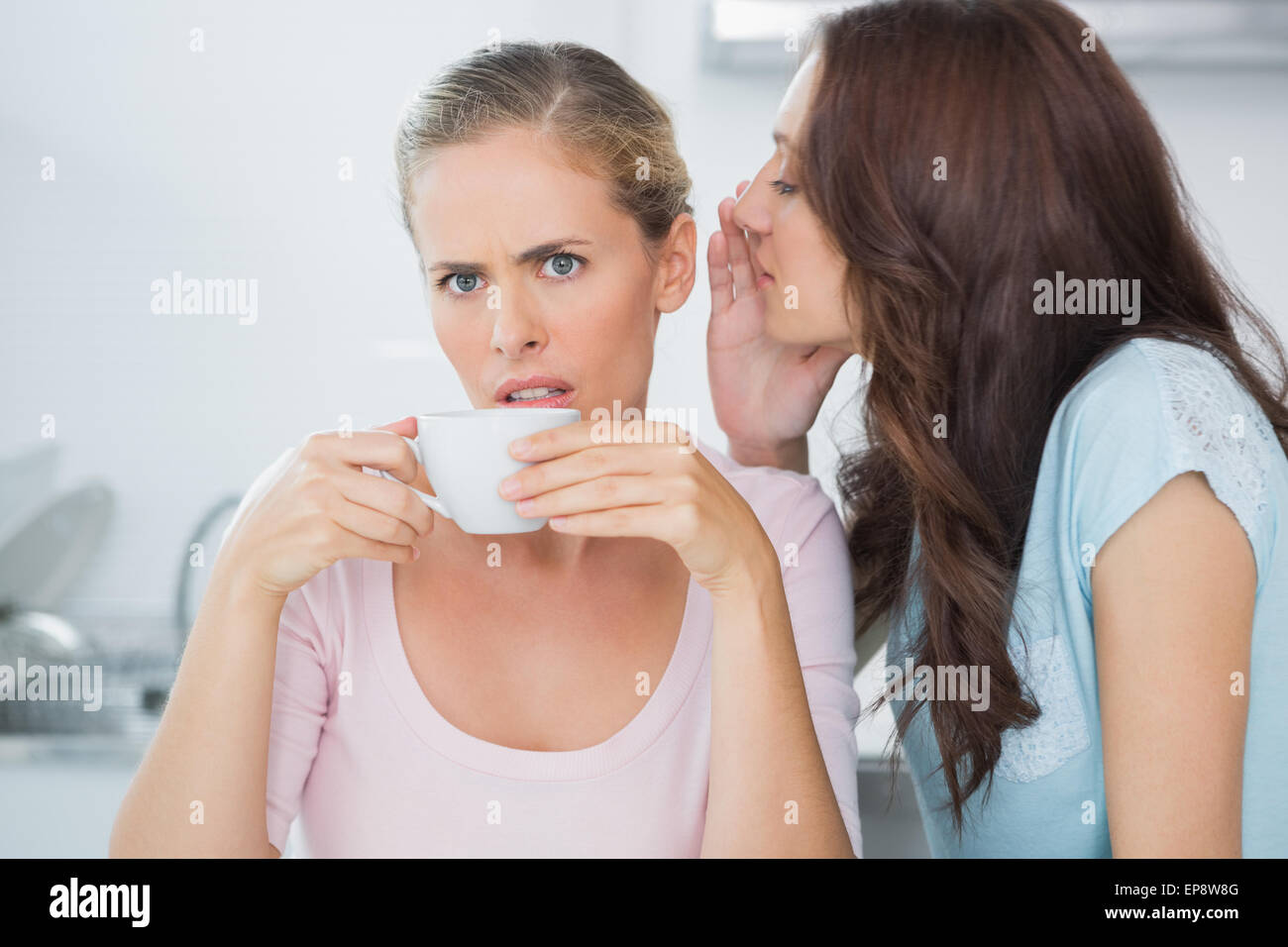 Brunette telling secret à son ami alors que la consommation de café Banque D'Images
