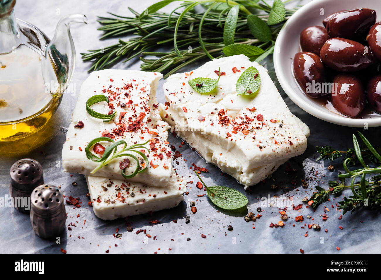 Le fromage Feta aux olives et d'herbes vertes sur fond de marbre gris Banque D'Images