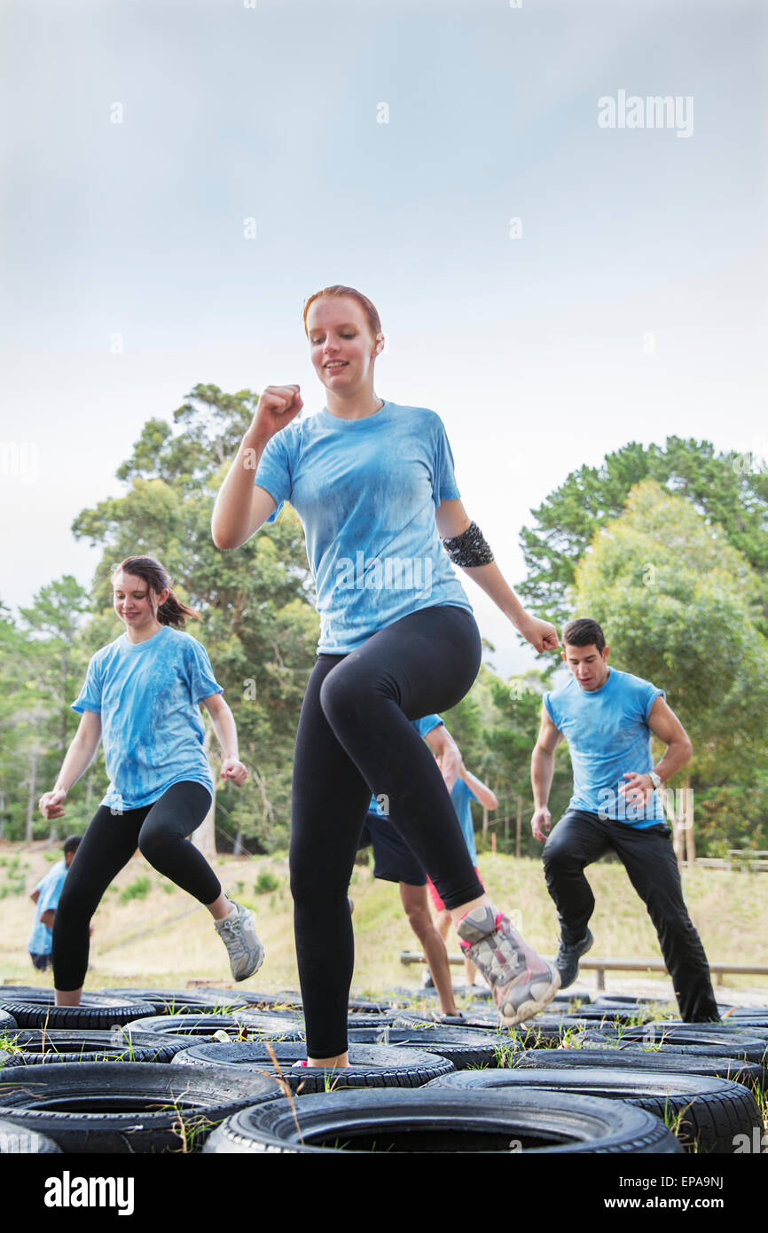 Femme sautant tire à obstacle boot camp Banque D'Images