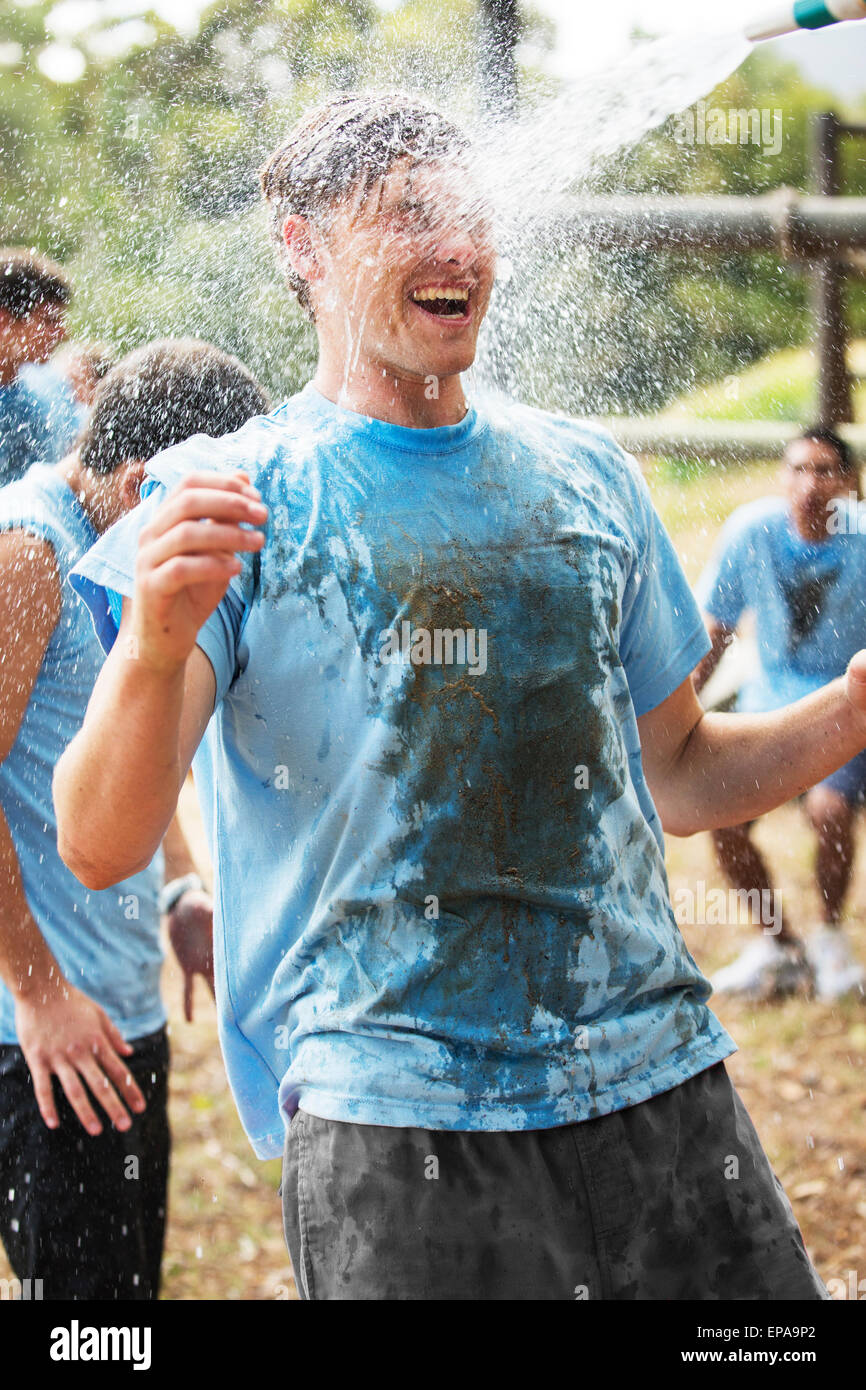 Man enjoying flexible d'eau de boot camp de pulvérisation Banque D'Images