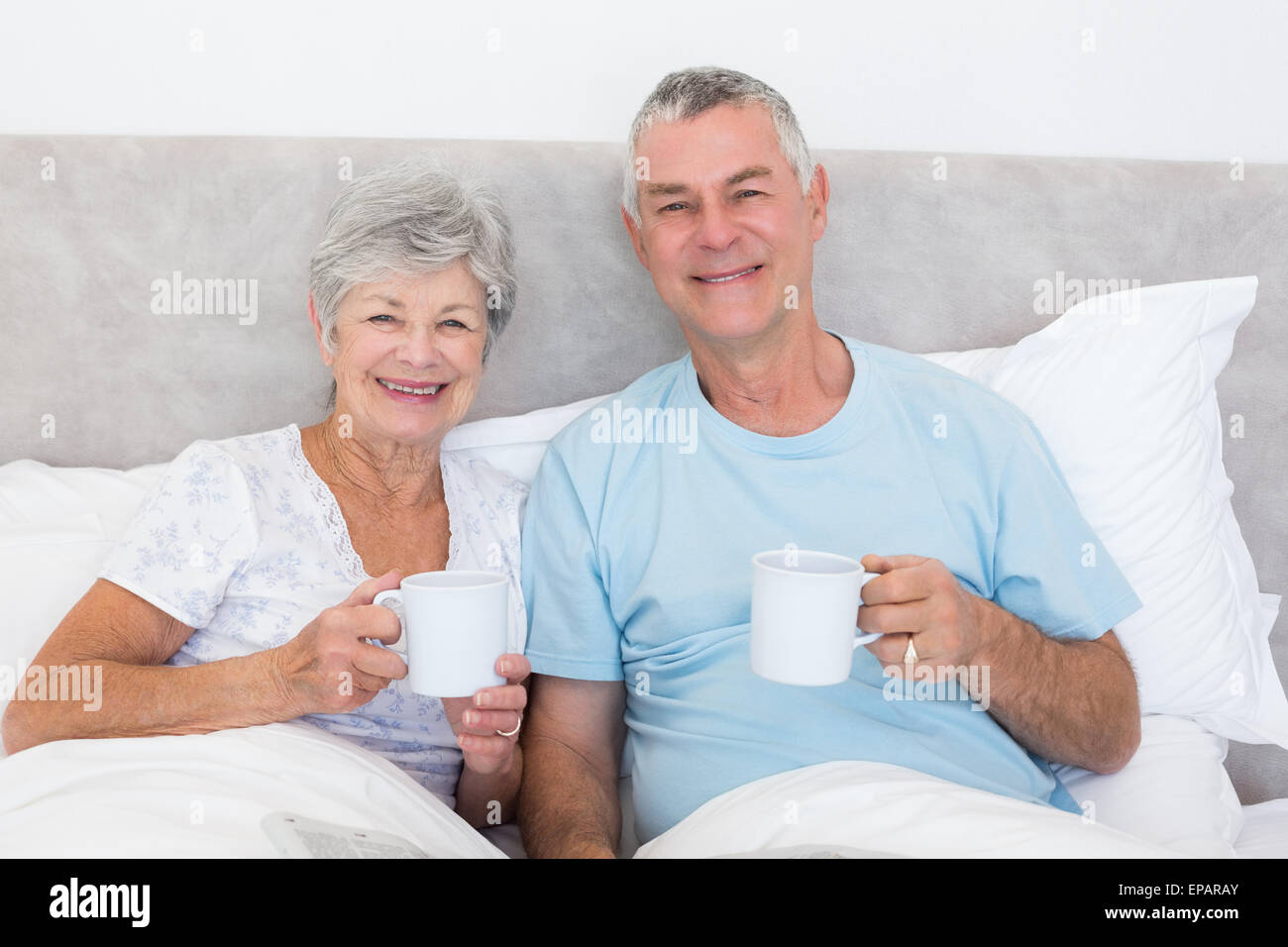 Senior couple holding tasses à café au lit Banque D'Images
