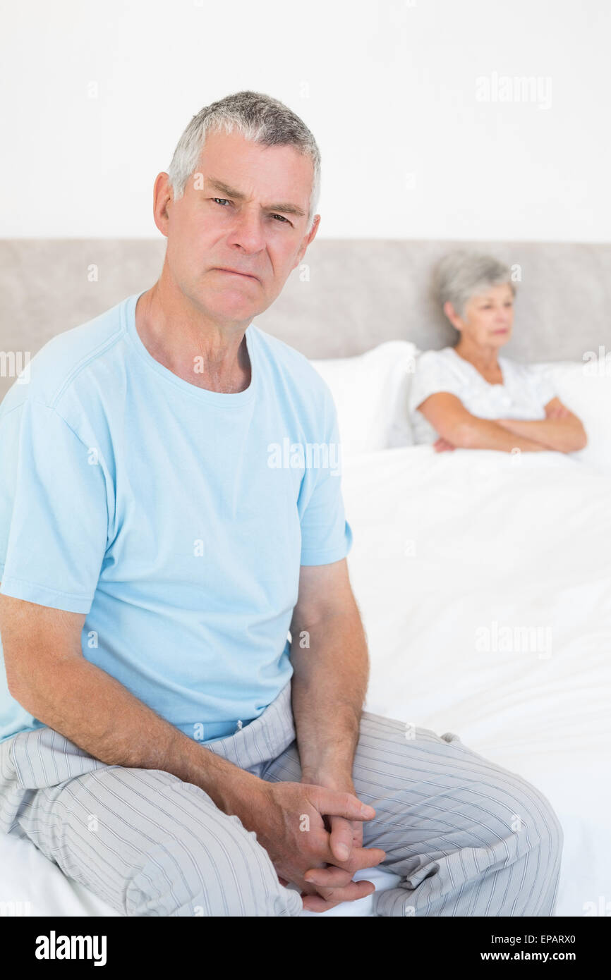 Angry Man on bed with woman in background Banque D'Images