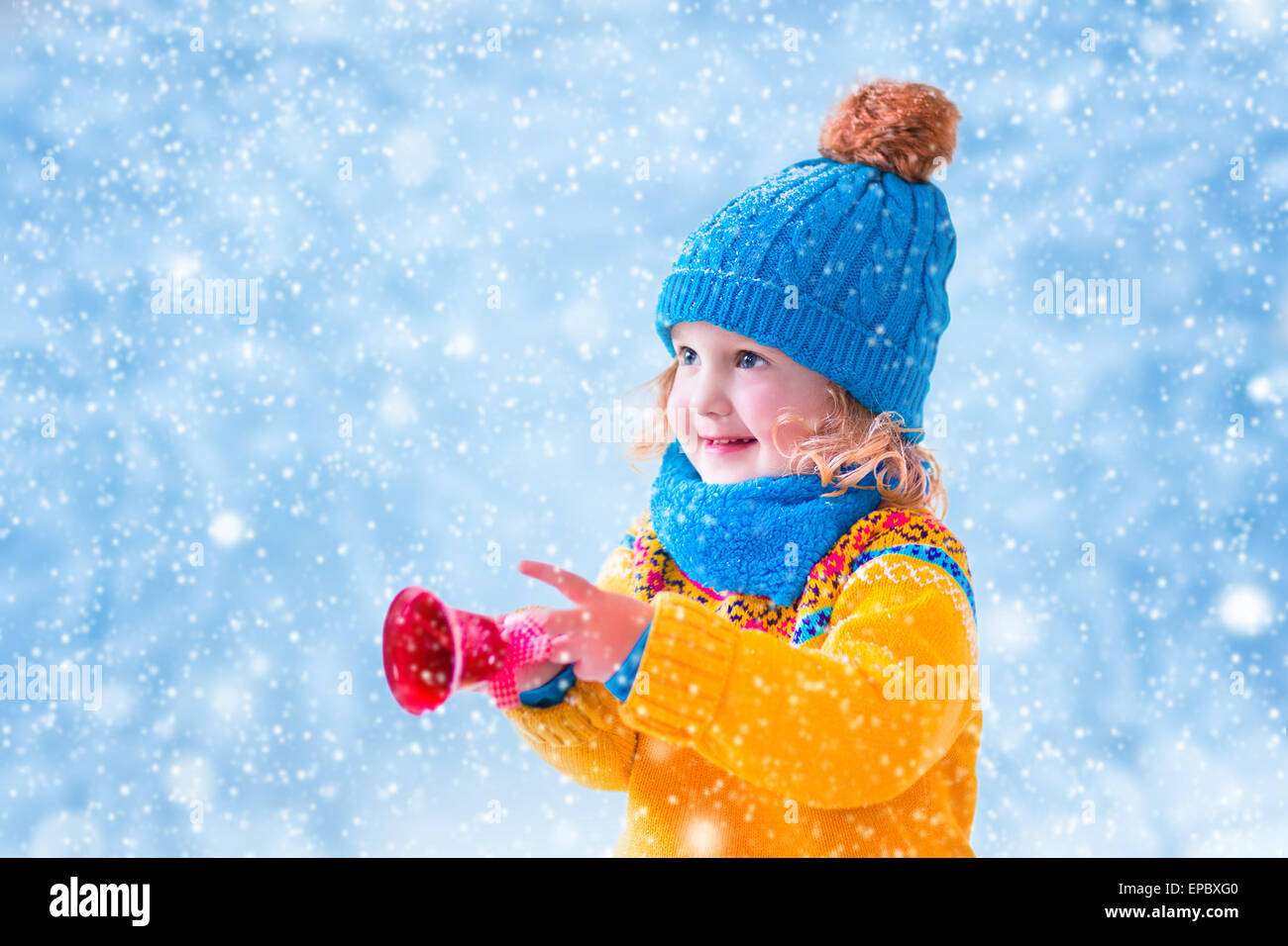 Fille adorable, mignon tout-petit dans un chapeau tricoté et yellow nordic chandail, jouer avec des jouets de Noël, flocons de neige de Bell Banque D'Images