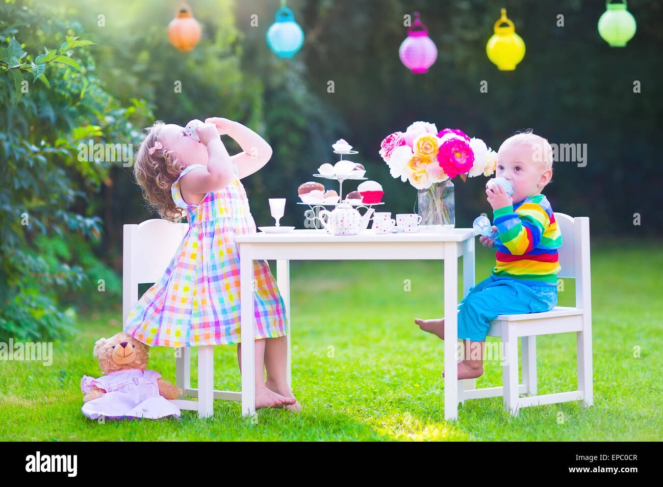 Deux enfants heureux, cute girl bouclés et un petit bébé garçon, frère et soeur, bénéficiant d'un thé avec leurs jouets Banque D'Images