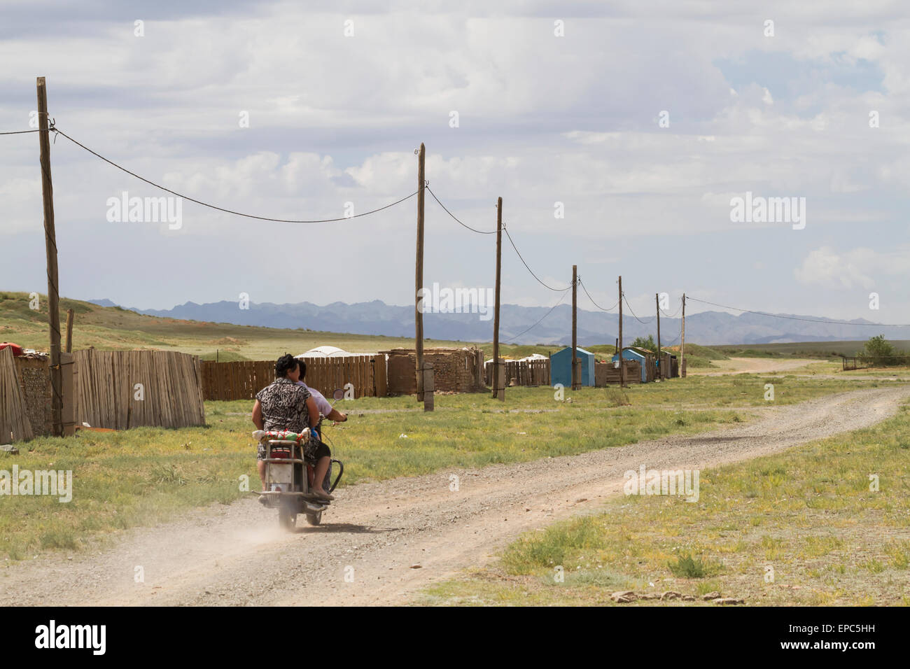 Les hommes sur une moto en bois par des clôtures et poteaux téléphoniques, Bulgan, Province Sud de Gobi, Mongolie Banque D'Images