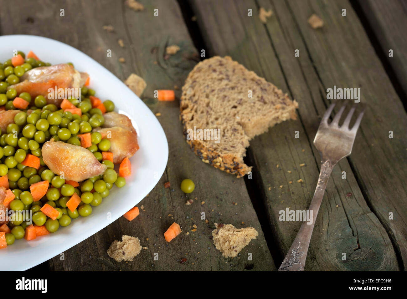 Ragoût de poulet avec des carottes et des pois verts sur fond rustique en bois Banque D'Images