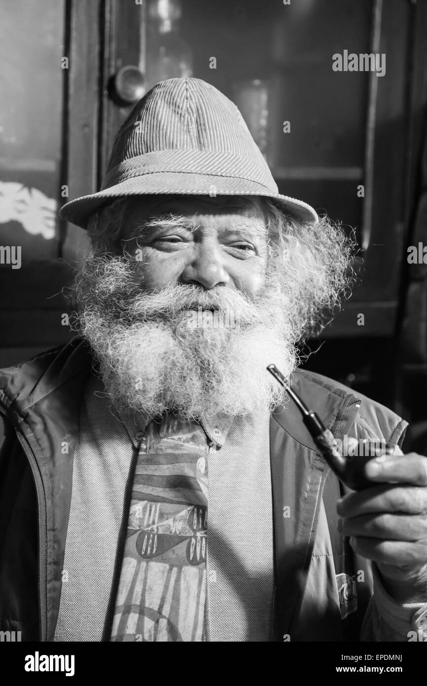 Vieil homme avec une longue barbe blanche fume une pipe Banque D'Images