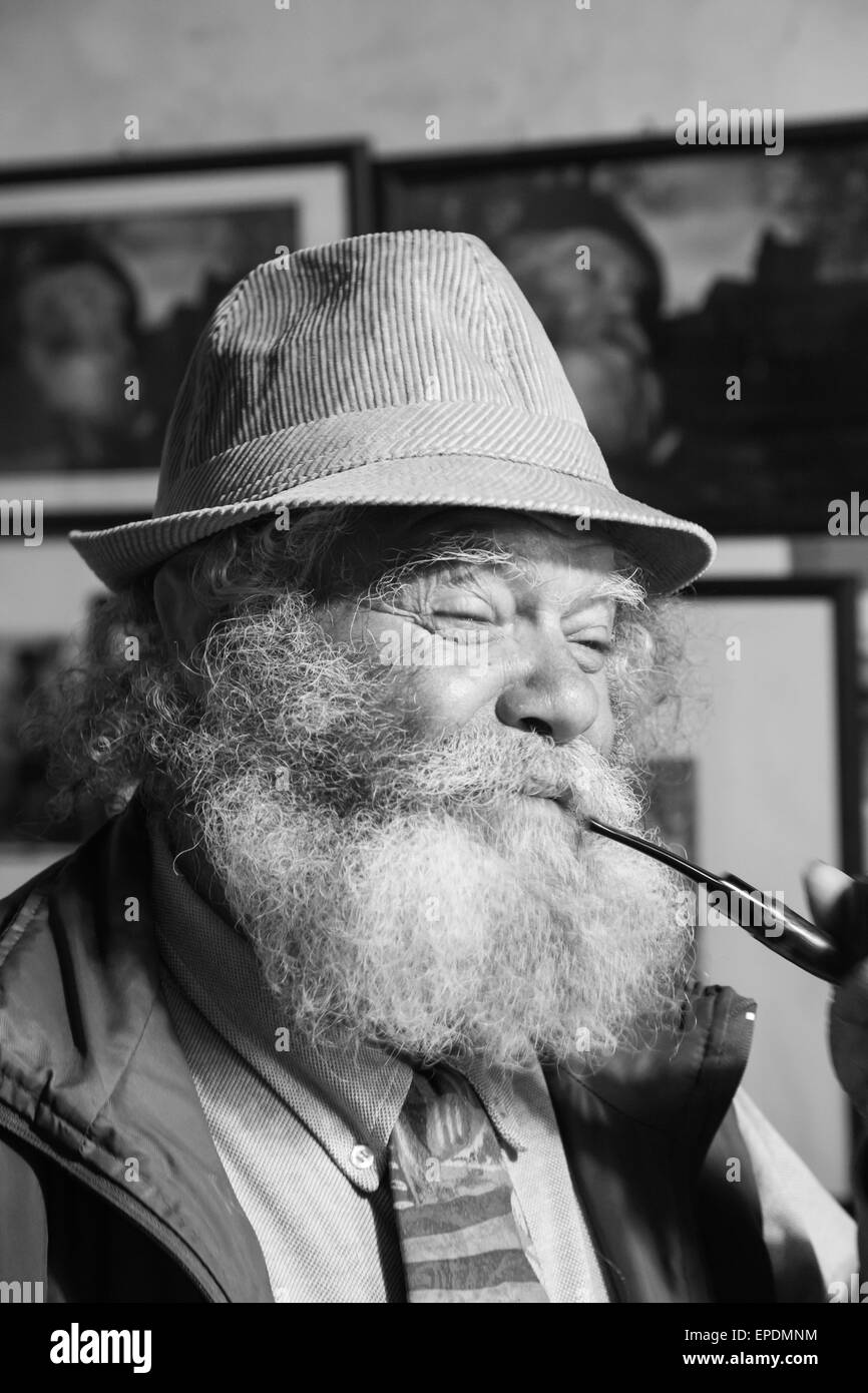 Vieil homme avec une longue barbe blanche fume une pipe Banque D'Images