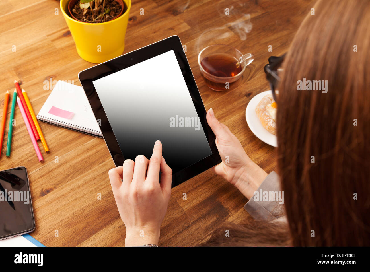 Jeune femme travaillant avec tablet mis sur bureau en bois avec écran blanc pour le texte. Prise de vue aérienne Banque D'Images