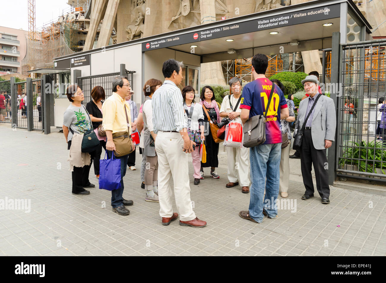 Groupe de touristes asiatiques en écoutant leur guide devant la cathédrale Sagrada Familia Banque D'Images
