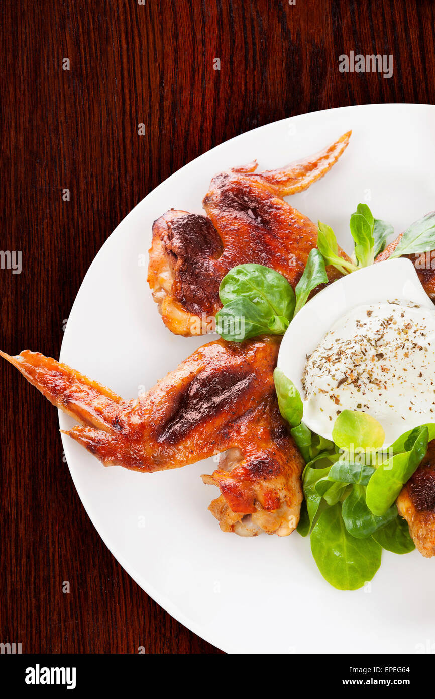 Buffalo wings délicieux avec une salade fraîche sur fond de bois brun. Manger culinaire. Banque D'Images