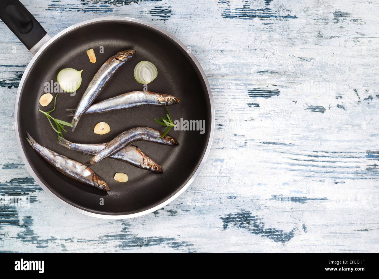 Manger des fruits de mer de la Méditerranée. Sardines fraîches sur pan noir sur blanc et bleu fond de bois texturé vue d'en haut. Fruits de mer Banque D'Images