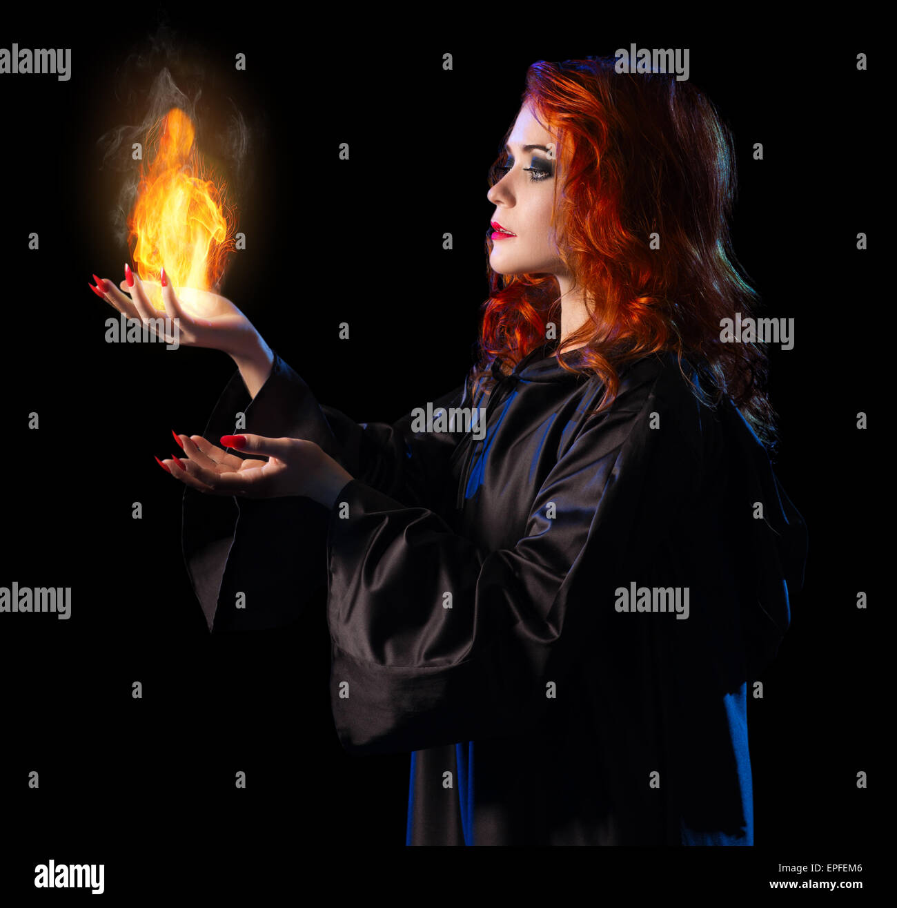Jeune sorcière avec flamme isolated on black Banque D'Images